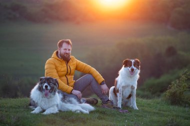 İnsan doğada köpekleriyle gün batımında.