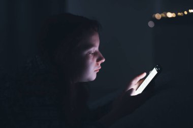 Akıllı telefon kullanan genç kız, gece geç saatte yatakta yatan tablet. Çocukların ekran bağımlılığı konsepti..