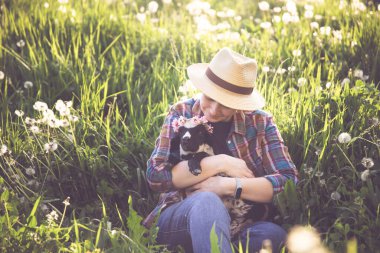 Baharda küçük şirin bir kuzuyu elinde tutan dişi çiftçi. Yeşil çimenler ve sihirli günbatımı..