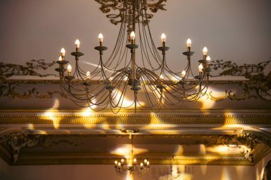 Zarif bir odanın içinde klasik bir avize. Tavandan sarkan pahalı, güzel bir avize. 