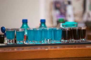 Bardaki mavi renkli likör bardaklarıyla dolu küçük bardakta içki.