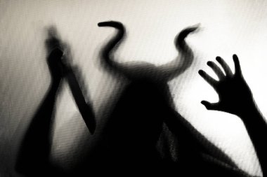 Karanlıkta, pencerenin arkasında elinde bıçak olan ürkütücü bir figür. Cadılar Bayramı geçmişi