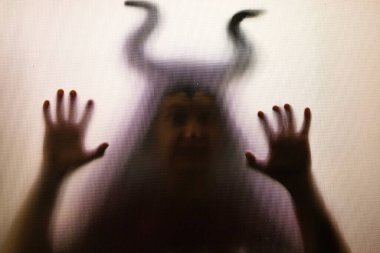 Karanlıkta, pencerenin arkasında boynuzları olan ürkütücü bir figür. Cadılar Bayramı geçmişi 