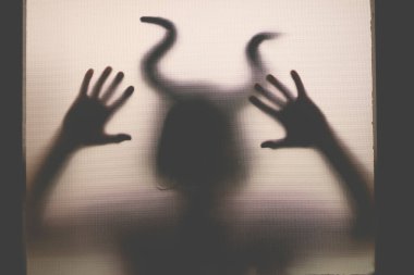 Karanlıkta, pencerenin arkasında boynuzları olan ürkütücü bir figür. Cadılar Bayramı geçmişi