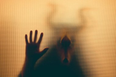 Karanlıkta, pencerenin arkasında boynuzları olan ürkütücü bir kafatası figürü