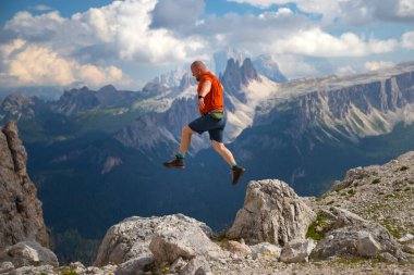 Gezgin ya da gezgin Dolomite dağlarında büyük kayalara atlıyor. Meydan okuma, risk ve özgürlük kavramı.