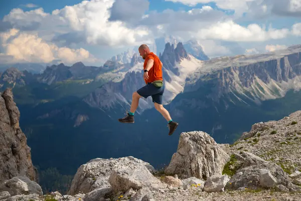 Gezgin ya da gezgin Dolomite dağlarında büyük kayalara atlıyor. Meydan okuma, risk ve özgürlük kavramı.