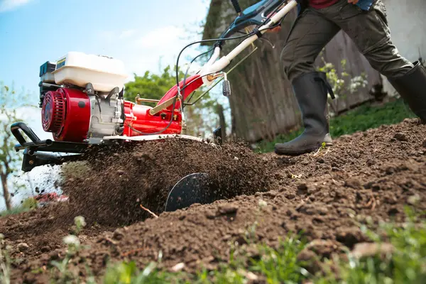 Organik tarım yapan adam toprağı bir dümenciyle işliyor toprağı ekime hazırlıyor.