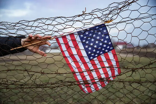 Zincirli tel örgüye bağlı bir Amerikan Bayrağı 'nı yakından çek. Amerikan göçmenlik ve ABD mülteci krizi kavramı