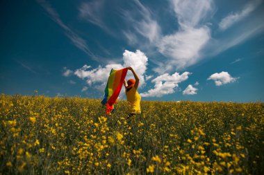 Çayırda LGTB bayrağı sallayan ikili olmayan kişi. LGBT gurur kavramı.
