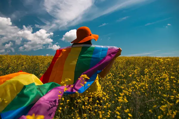 Çayırda LGTB bayrağı sallayan ikili olmayan kişi. LGBT gurur kavramı.