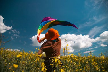 Çayırda LGTB bayrağı sallayan ikili olmayan kişi. LGBT gurur kavramı.
