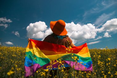 Çayırda LGTB bayrağı sallayan ikili olmayan kişi. LGBT gurur kavramı