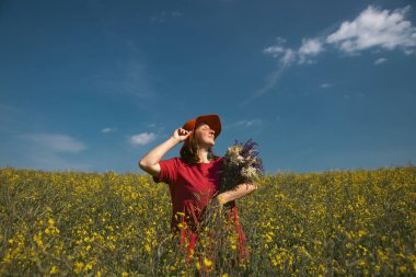 Güzel bir kadın elinde bir buket yaban çiçeği tutuyor, muhteşem doğanın tadını çıkarıyor. Yaz yaşam tarzı konsepti.