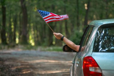 Gün batımında Amerikan bayrağı taşıyan bir adam. Bağımsızlık Günü ya da Amerika 'da seyahat.