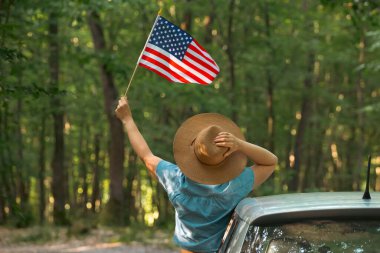 Gün batımında Amerikan bayrağı taşıyan bir kadın. Bağımsızlık Günü ya da Amerika 'da seyahat.