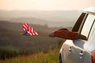 Gün batımında Amerikan bayrağı taşıyan bir adam. Bağımsızlık Günü ya da Amerika 'da seyahat.