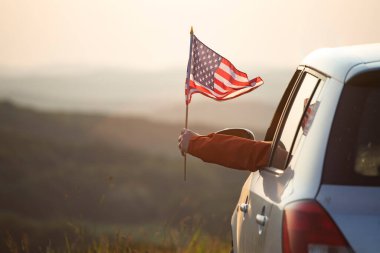 Gün batımında Amerikan bayrağı taşıyan bir adam. Bağımsızlık Günü ya da Amerika 'da seyahat.