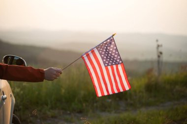 Gün batımında Amerikan bayrağı taşıyan bir adam. Bağımsızlık Günü ya da Amerika 'da seyahat.