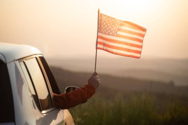 Gün batımında Amerikan bayrağı taşıyan bir adam. Bağımsızlık Günü ya da Amerika 'da seyahat.