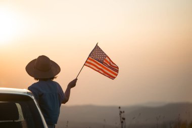 Gün batımında Amerikan bayrağı taşıyan bir kadın. Bağımsızlık Günü ya da Amerika 'da seyahat.