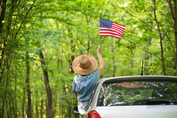 Gün batımında Amerikan bayrağı taşıyan bir kadın. Bağımsızlık Günü ya da Amerika 'da seyahat.