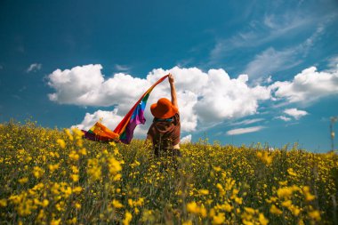 Çayırda LGTB bayrağı sallayan ikili olmayan kişi. LGBT gurur kavramı.