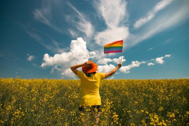 Elinde Gay Gökkuşağı Bayrağı olan bir kadın. Aynı cinsiyet çiftleri için mutluluk, özgürlük ve aşk kavramı