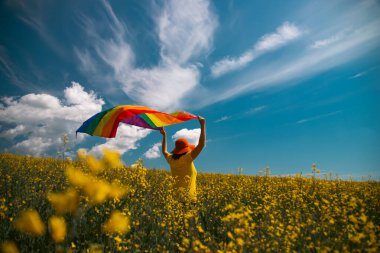 Çayırda LGTB bayrağı sallayan ikili olmayan kişi. LGBT gurur kavramı.