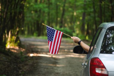 Gün batımında Amerikan bayrağı taşıyan bir adam. Bağımsızlık Günü ya da Amerika 'da seyahat.