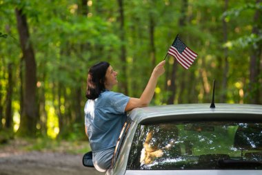 Gün batımında Amerikan bayrağı taşıyan bir kadın. Bağımsızlık Günü ya da Amerika 'da seyahat.