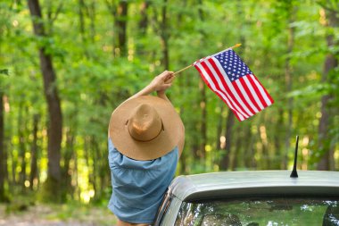 Gün batımında Amerikan bayrağı taşıyan bir kadın. Bağımsızlık Günü ya da Amerika 'da seyahat.