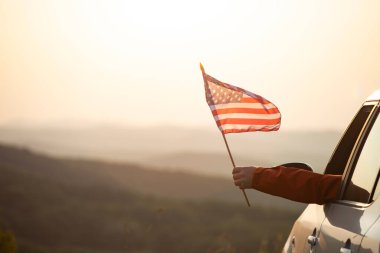 Gün batımında Amerikan bayrağı taşıyan bir adam. Bağımsızlık Günü ya da Amerika 'da seyahat.
