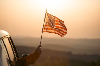 Gün batımında Amerikan bayrağı taşıyan bir adam. Bağımsızlık Günü ya da Amerika 'da seyahat.