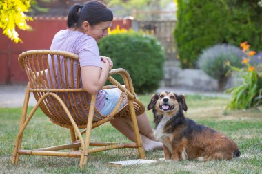 Sıradan, orta yaşlı bir kadın bahçede küçük kahverengi köpeğiyle eğleniyor. Hayvanlarla bağ kurma ve birlikte olmaktan keyif alma kavramı.