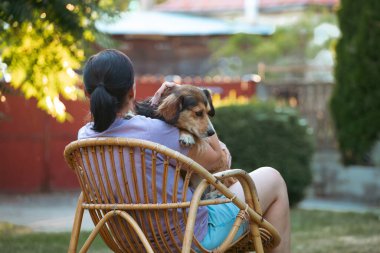 Sıradan, orta yaşlı bir kadın bahçede küçük kahverengi köpeğiyle eğleniyor. Hayvanlarla bağ kurma ve birlikte olmaktan keyif alma kavramı.