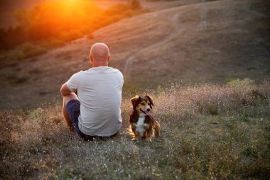 Doğada bir adam ve köpeği güzel bir gün batımında.