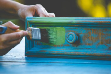 İnsan eli tebeşirle ahşap mobilya boyuyor. Yepyeni renkli tebeşir boyasıyla eski moda ahşap mobilyaları yeniliyorum. Ev dekorasyonu yeniden biçimlendiriliyor