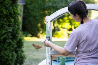 Orta yaşlı bir kadın ahşap mobilya boyuyor. Yepyeni renkli tebeşir boyasıyla eski moda ahşap mobilyaları yeniliyorum. Ev dekorasyonu yeniden biçimlendiriliyor