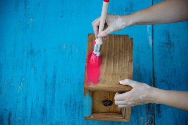 İnsan eli tebeşirle ahşap mobilya boyuyor. Yepyeni renkli tebeşir boyasıyla eski moda ahşap mobilyaları yeniliyorum. Ev dekorasyonu yeniden biçimlendiriliyor