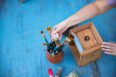 İnsan eli tebeşirle ahşap mobilya boyuyor. Yepyeni renkli tebeşir boyasıyla eski moda ahşap mobilyaları yeniliyorum. Ev dekorasyonu yeniden biçimlendiriliyor