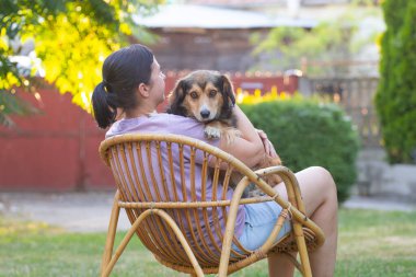 Sıradan, orta yaşlı bir kadın bahçede küçük kahverengi köpeğiyle eğleniyor. Hayvanlarla bağ kurma ve birlikte olmaktan keyif alma kavramı.