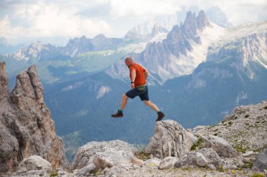 Gezgin ya da gezgin Dolomite dağlarında büyük kayalara atlıyor. Meydan okuma, risk ve özgürlük kavramı.