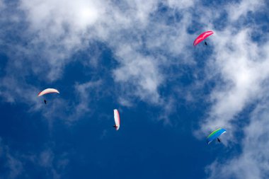 Mavi gökyüzünde bulutlarla uçan paragliderler. Macera konsepti..