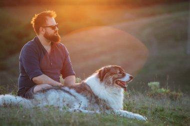 İnsan ve köpeği güzel günbatımının tadını çıkarıyor.