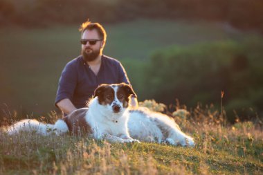 İnsan ve köpekleri güzel günbatımının tadını çıkarıyor.