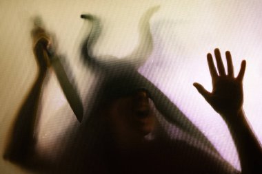 Karanlıkta, pencerenin arkasında elinde bıçak olan ürkütücü bir figür. Cadılar Bayramı geçmişi