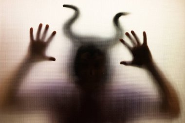 Karanlıkta, pencerenin arkasında boynuzları olan ürkütücü bir figür. Cadılar Bayramı geçmişi