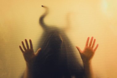 Karanlıkta, pencerenin arkasında boynuzları olan ürkütücü bir figür. Cadılar Bayramı geçmişi