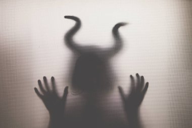 Karanlıkta, pencerenin arkasında boynuzları olan ürkütücü bir figür. Cadılar Bayramı geçmişi